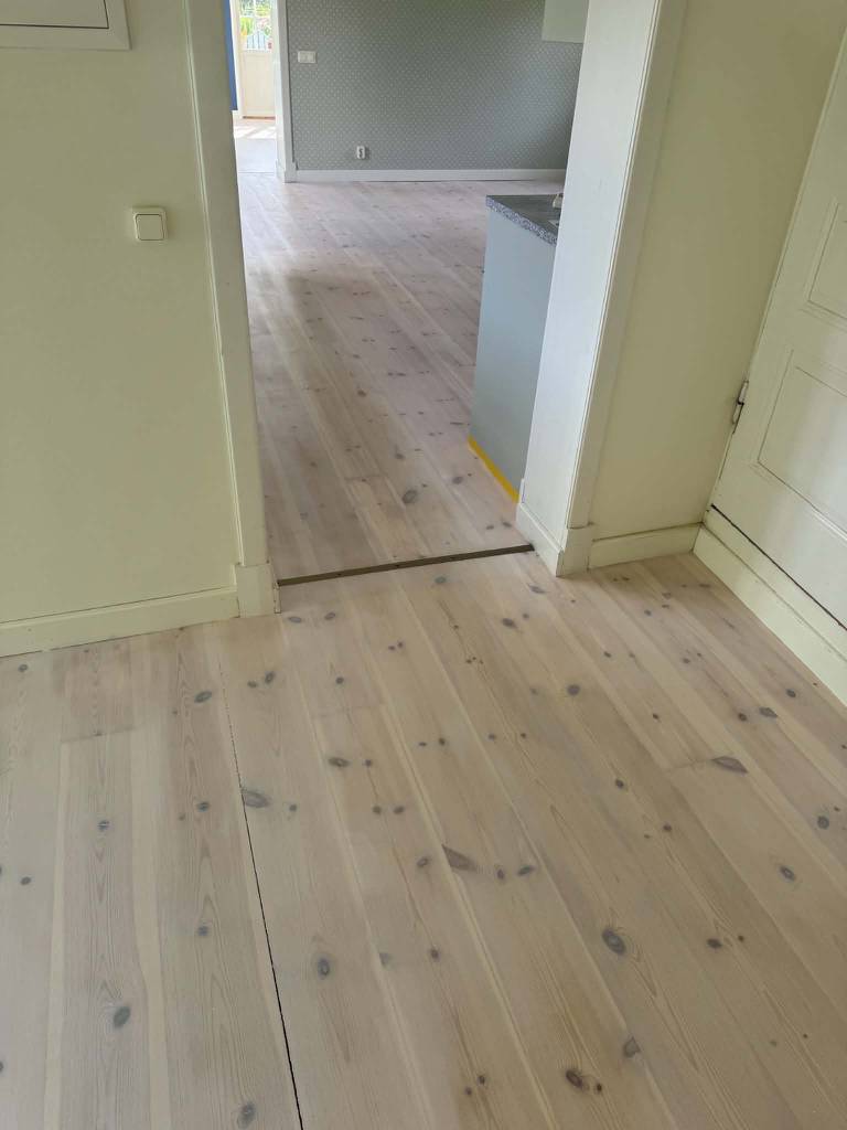 Bild 1 av referensprojekt Renovering av kraftigt slitet trägolv – slipning & vitvaxad finish